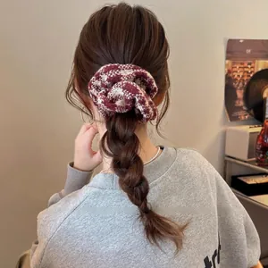 Detail of red and white checkered knit scrunchie styled on a braided ponytail
