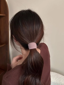 Dettaglio di un elastico per capelli largo rosa antico su un'acconciatura a coda di cavallo