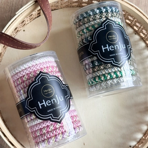 Detailed view of elastic woven hair bands in various colors packaged in clear containers