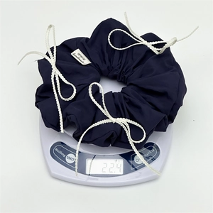 Blue bow scrunchie on electronic scale showing precise product weight of 22.4g