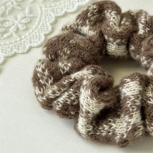 Close-up of brown and white plaid knit scrunchie with soft wool texture for hair