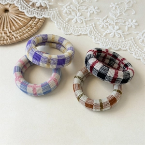 Detailed view of four thick plaid fabric hair ties in various vintage pastel check patterns