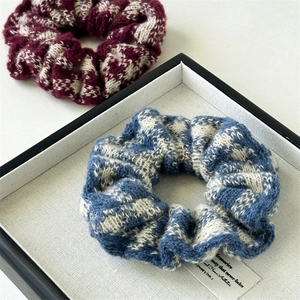 Detail of blue and white checkered knit scrunchie with soft woven texture on a tray