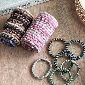 Elastic braided hair ties set for high ponytails in various colors on wooden surface