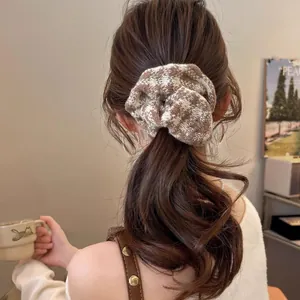 Close-up of a brown checkered knit scrunchie styled on a woman's hair in a warm setting