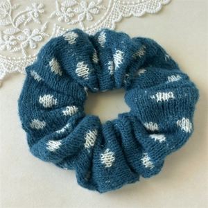 Close-up of navy blue knitted scrunchie with white polka dots and fuzzy wool texture
