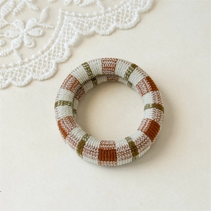 Close-up of thick knitted plaid scrunchie with orange and green woven texture