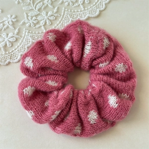 Detail view of pink knitted scrunchie with white dots and soft textured wool fabric