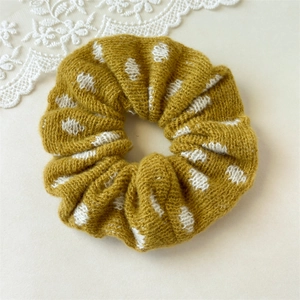 Detailed knit texture of mustard yellow scrunchie with white plush polka dot pattern