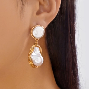 Gros plan de boucles d'oreilles asymétriques chat et poisson avec perles baroques