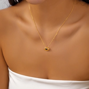 Detail of golden Evil Eye necklace with blue sapphire center and white diamonds on a model