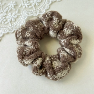 Close-up of knit scrunchie with brown checkered pattern and white lace detail