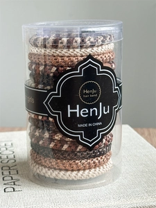 Detailed view of elastic braided hair ties in various brown shades packed in a clear round box