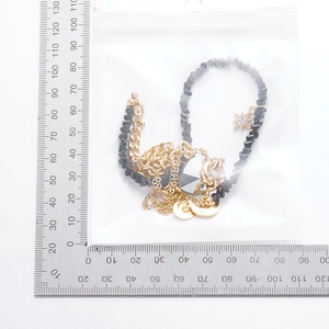 Measurement of layered gold star pendant and black bead necklace in packaging