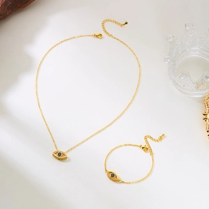Detailed close-up of golden evil eye necklace and bracelet set with blue gemstone