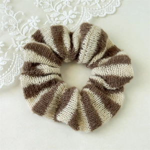 Détail d'un chouchou en tricot rayé marron et crème avec une texture en mohair