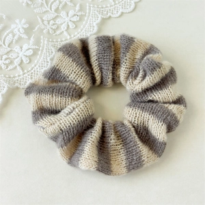 Détail d'un chouchou tricoté à rayures gris et blanc cassé en texture laine