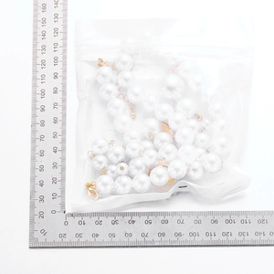 Detail of white faux pearl necklace with measurement ruler showing bead size and length