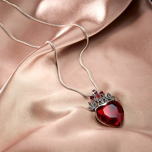 Gothic vintage heart red gemstone pendant necklace with silver crown on satin background