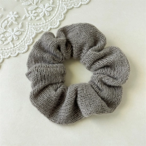 Gros plan du chouchou tricoté gris avec plis en tissu doux sur fond de dentelle blanche