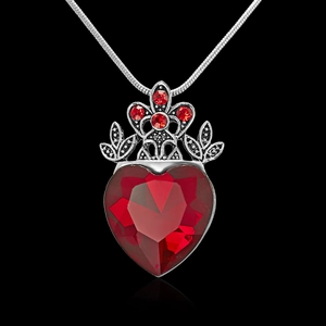 Macro view of gothic crown pendant with heart-shaped red gemstone and snake chain