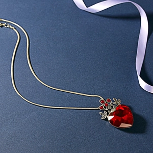 Gothic vintage heart pendant necklace with red crystal and gold chain on blue background