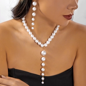 Detail of elegant Y-shaped pearl necklace and matching drop earrings on model neck