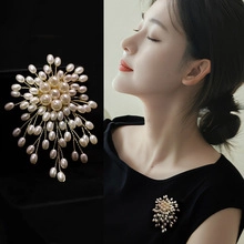 Dettaglio di un'elegante spilla floreale con perle su fondo nero e indossata da modella