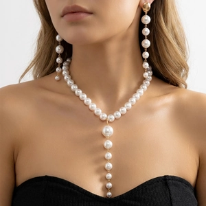 Detail of vintage tassel pearl Y-necklace and drop earrings set on female model