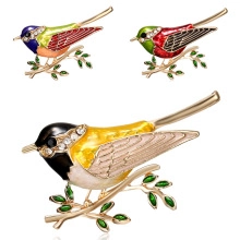 Dettaglio di tre spille a forma di uccello in smalto colorato con placcatura in oro