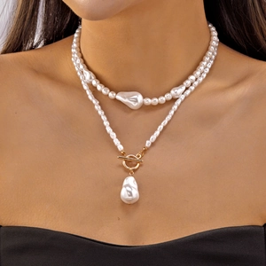 Détail d'un collier de perles double couche avec pendentif baroque et fermoir OT doré