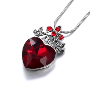 Macro shot of gothic heart necklace with faceted red gemstone and floral silver detail