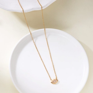 Elegant gold oval zircon pendant necklace on a white ceramic tray with soft lighting