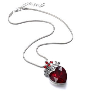 Macro shot of a red heart-shaped gemstone pendant on a silver snake chain necklace
