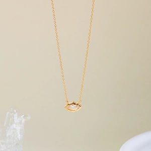 Detailed close-up of a gold necklace with a marquise-cut zircon pendant and cross chain