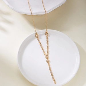 Macro view of gold Y-shaped pendant necklace featuring geometric clear zircon accents
