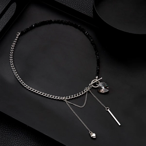Detail view of heart pendant and cross chain necklace on a black matte tray background