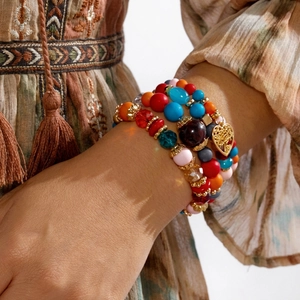Detail von mehrlagigen Boho-Perlenarmbändern mit bunten Perlen und Herz-Baum-Anhänger
