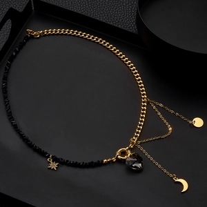 Detailed view of asymmetric necklace featuring black crystal heart and gold crescent charms