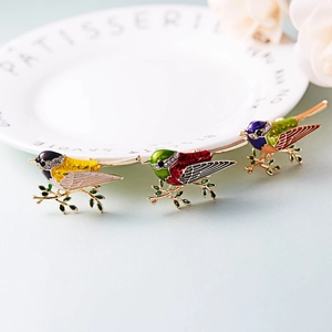 Detailed close-up of three enamel bird brooches with rhinestones on a golden vine branch