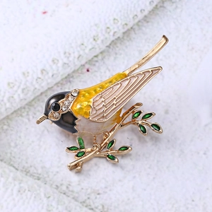 Detailed close-up of enamel bird brooch with sparkling rhinestones on golden branch
