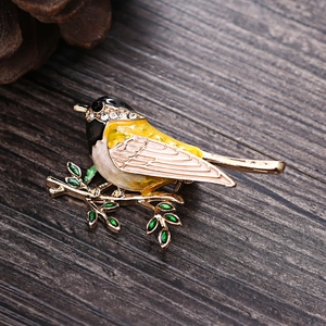 Detailed view of enamel bird brooch with sparkling rhinestones on a gold branch