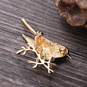 Detail view of bird brooch back with golden texture and pin clasp on wood surface