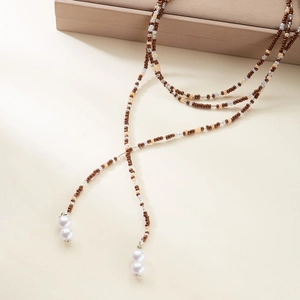 Dettaglio di una lunga collana di perline artigianale con cristalli marroni e perle bianche