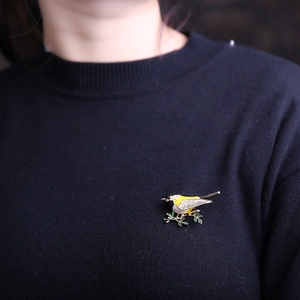 Detail of enamel swallow bird brooch with crystals pinned on a navy blue sweater