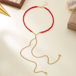 Dettaglio della collana di perline rosse con ciondoli a stella dorati e catene a frange