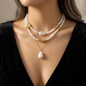 Détail d'un collier de perles à trois rangs avec pendentif baroque et accents dorés