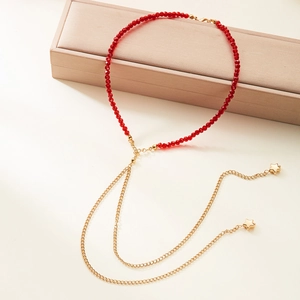 Collana lunga con perle di cristallo rosso e nappe a stella dorate su portagioie