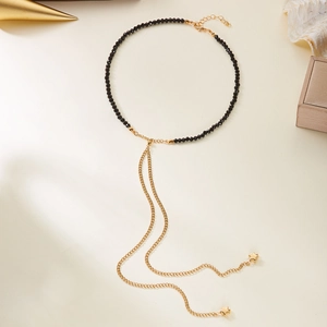 Dettaglio di perline nere e nappe dorate con ciondoli a stella su collana di lusso