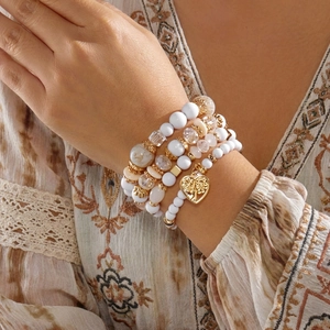 Detail eines mehrlagigen Boho-Perlenarmband-Sets mit Lebensbaum-Herzanhänger